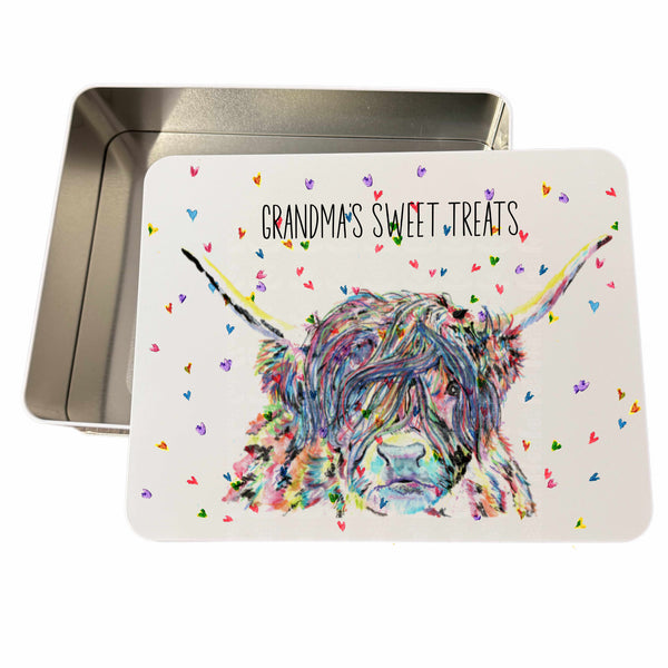 A personalised metal biscuit tin with a hand-drawn watercolor illustration of a Highland cow on the lid, customized with text 'Grandma's Sweet Treats'. The tin is open, revealing a silver interior.